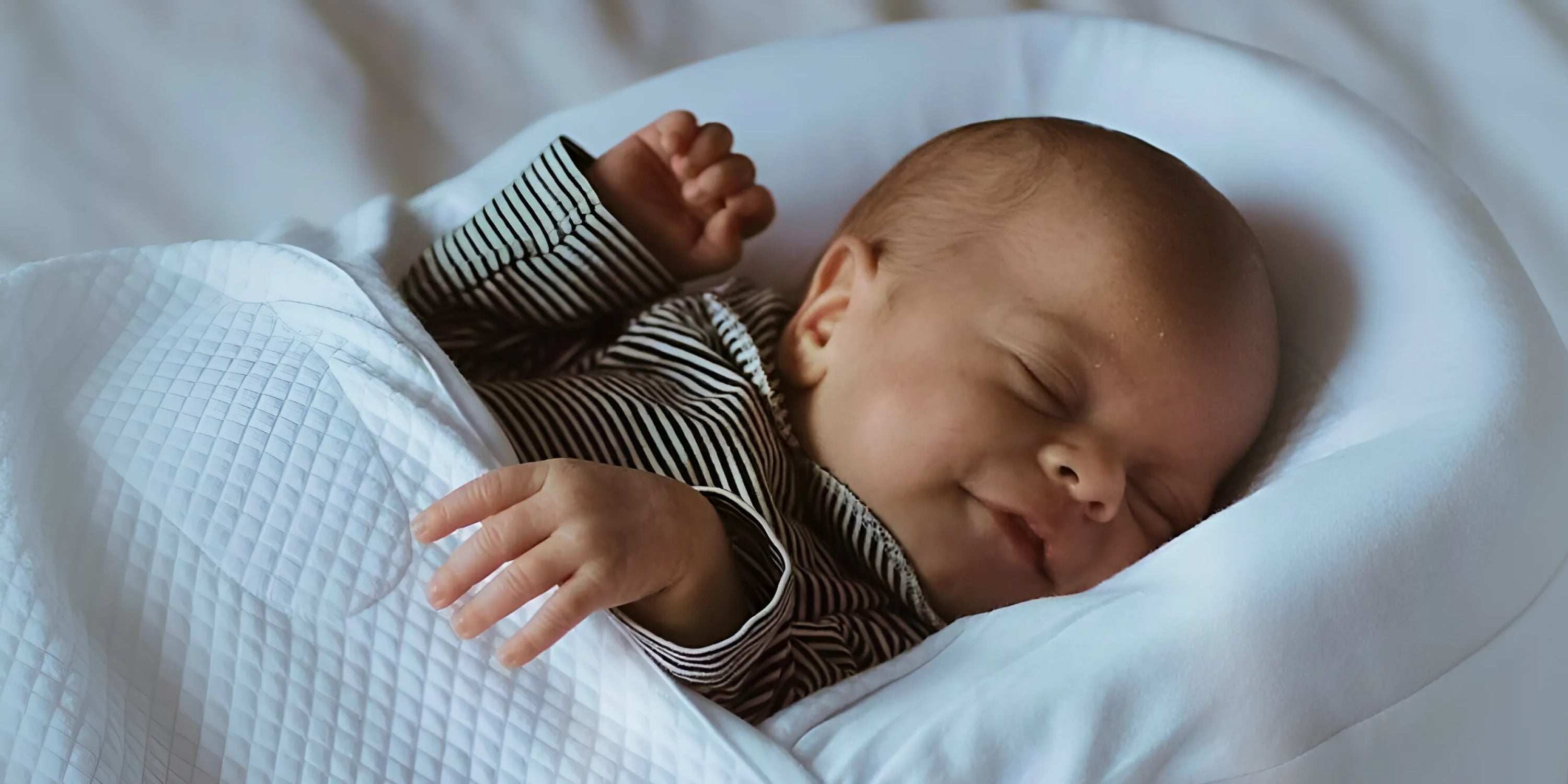 alt="Bebê dormindo confortável com produtos da Varialle - Cuidado e amor nos primeiros momentos"